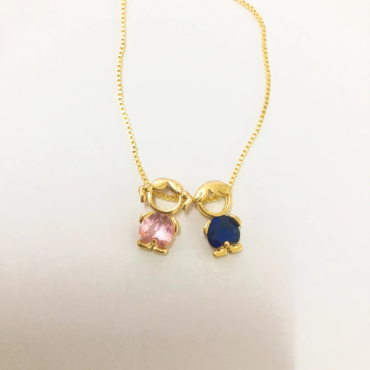Collar Familia con dos figuritas: una niña con piedra rosa y un niño con piedra azul