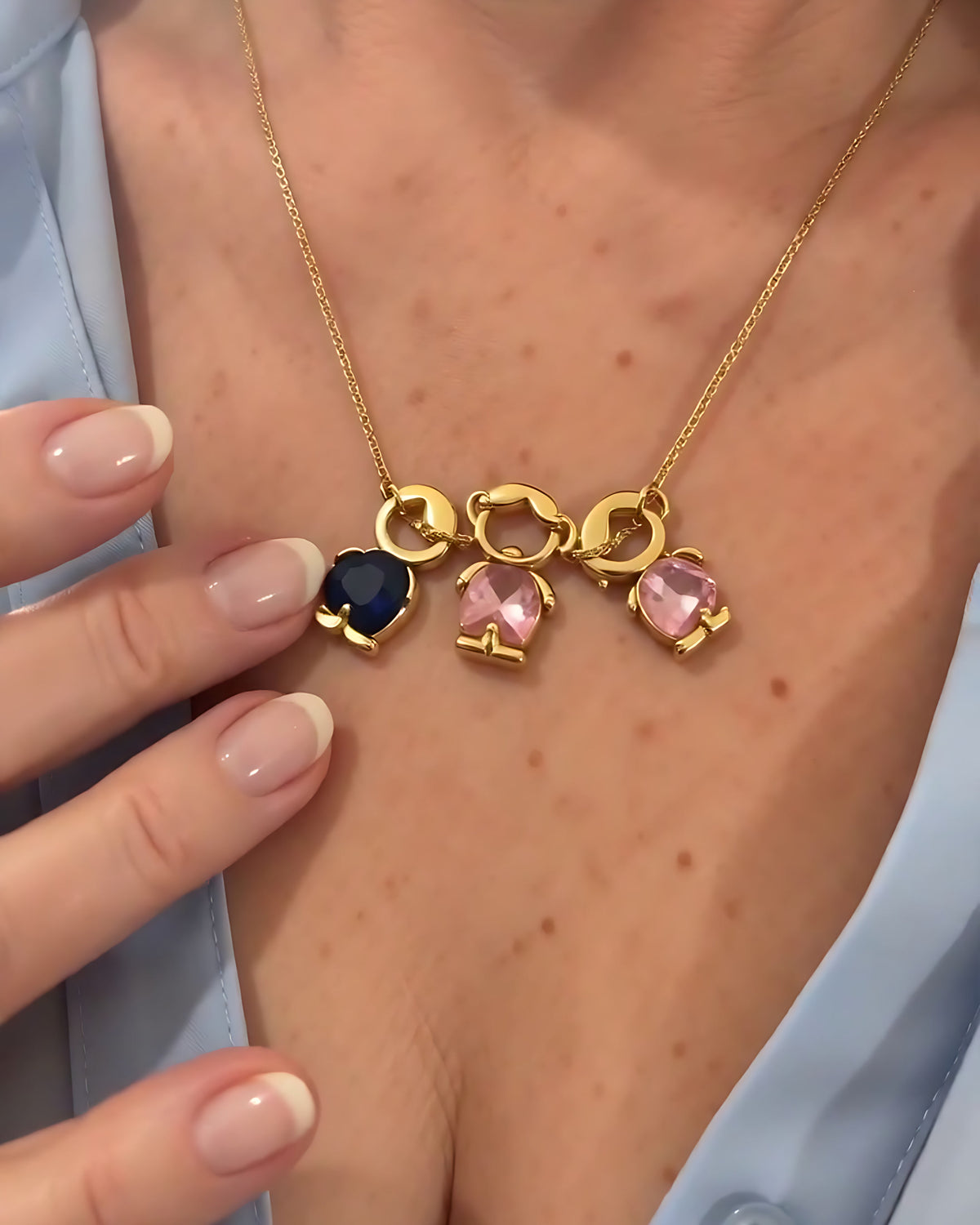 Collar Familia puesto con tres figuritas: un niño con piedra azul y dos niñas con piedra rosa
