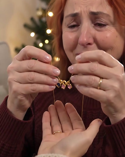 Madre emocionada sosteniendo el Collar Familia junto al árbol de Navidad